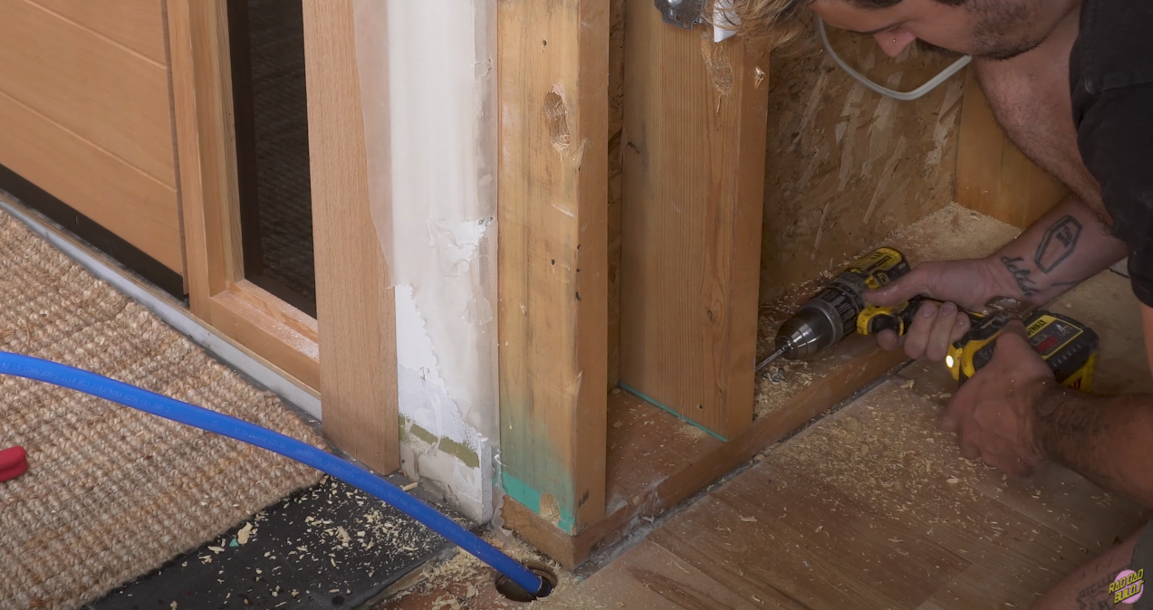 Drilling holes for the new plumbing to run through the studs.